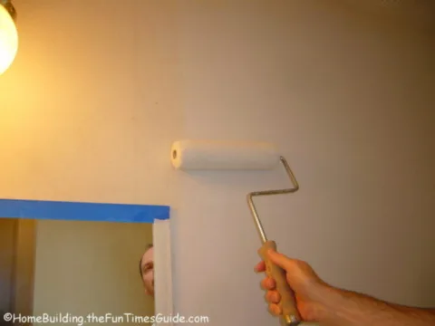 blue painters tape and rolling primer on drywall